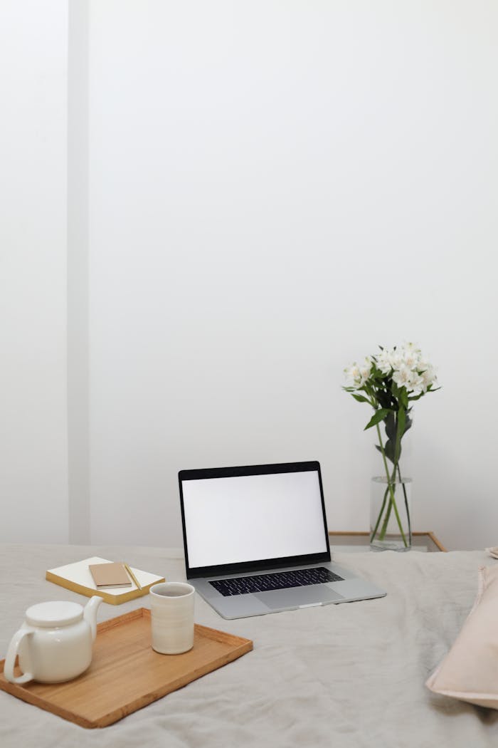 services-04 Wooden tray with tea set placed on comfortable bed near opened laptop and notebooks during remote work at home